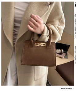 Dettaglio borsa in camoscio marrone scuro con fibbia dorata portata dalla modella