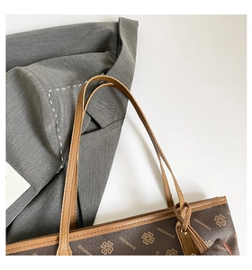 Close-up of brown patterned tote bag with clover prints on a grey suit jacket