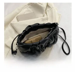 Detail showing the internal storage capacity of a black pleated pouch bag with shoulder strap