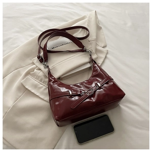 Détail du sac sous le bras en cuir verni bordeaux avec boucle argentée et sangle