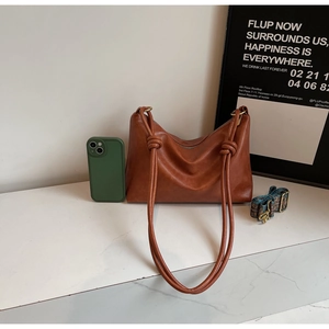 Brown vintage shoulder bag detail featuring knot design and ethnic pattern strap