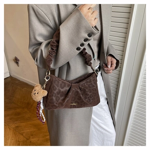 Detail of leopard print underarm bag with a cute plush bear charm and ribbon