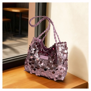 Detail of purple sequin tote bag with braided shoulder strap on a wooden surface