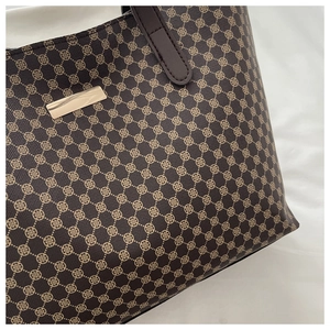 Detail of vintage monogram pattern and gold logo plaque on a brown tote bag