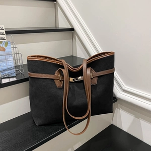 Sac fourre-tout noir minimaliste avec bandoulières en cuir marron sur une marche