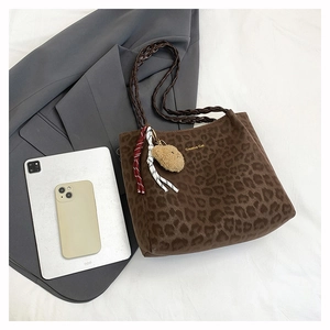 Detail of dark coffee leopard print tote bag with woven handles and plush bear charm