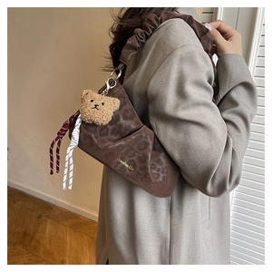 Detail of leopard print shoulder bag with Creative Cat text and plush bear pendant
