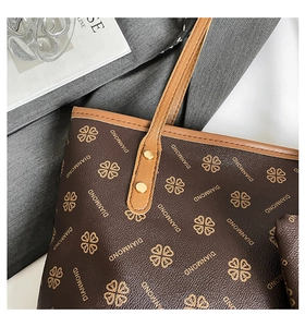 Detailed close-up of dark brown printed tote bag with leather handle and gold rivet