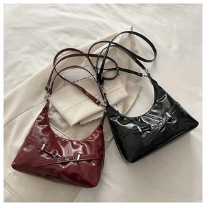 Détail de sacs à bandoulière en cuir verni brillant bordeaux et noir sur un costume