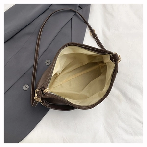 Detail view of the spacious light beige interior lining and gold zipper of the suede tote bag