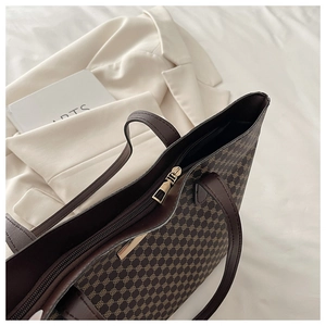 Detailed macro view of the geometric plaid print and golden metal zipper on the tote bag