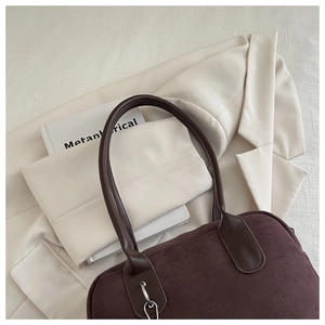 Detail of minimalist dark brown suede handbag with leather handle and silver metal hardware