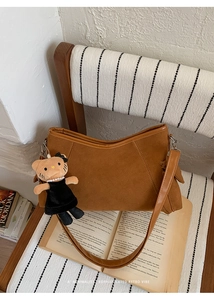 Brown faux leather square bag with cute cat charm placed on a vintage book