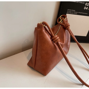 Detail of brown PU leather tote bag with decorative knot strap and gold metal ring