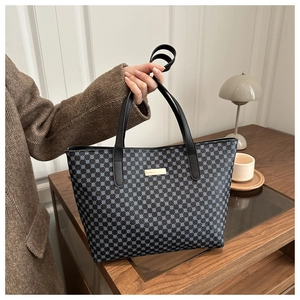 Detail of blue geometric circle pattern tote bag with gold metal logo plate and black straps