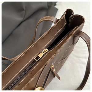 Close-up of vintage brown tote bag with gold zipper closure and fine stitching details