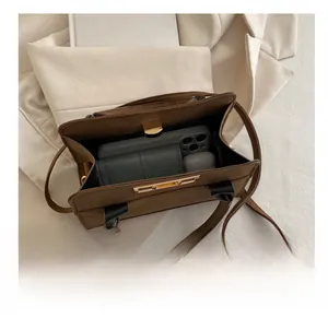 Vista dettagliata dell'ampio interno di una borsa a tracolla marrone scuro con oggetti comuni