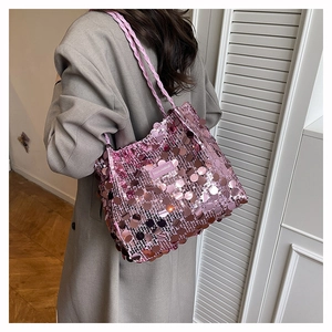 Dettaglio della borsa tote con paillettes rosa e spalline intrecciate su una modella