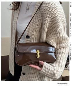 Detail shot of a dark brown glossy PU leather handbag with a golden clasp and buckle