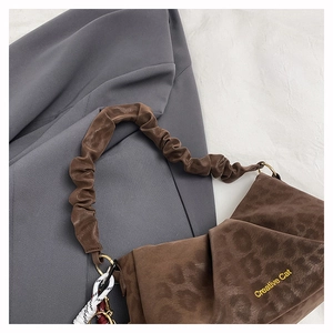 Detail of a brown leopard print shoulder bag featuring textured fabric and a gold logo