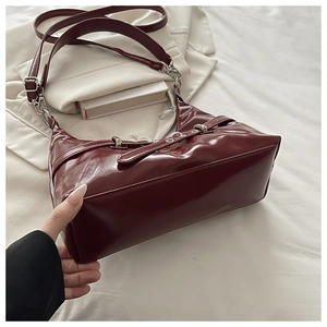 Vue détaillée du sac sous le bras rouge vin brillant avec boucle argentée et cuir verni
