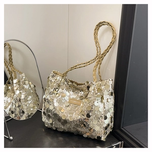 Close-up of sparkling gold sequin tote bag with woven handle and brand tag on mirror