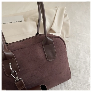Detail view of dark brown suede handbag featuring a premium leather handle and metal hook