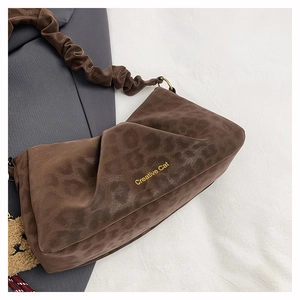 Detail view of leopard print shoulder bag with plush bear charm and gold metal rings