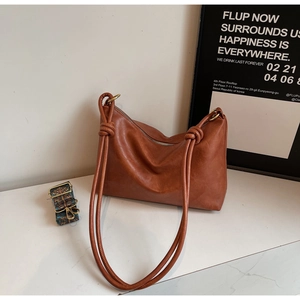 Brown leather tote with a large knotted handle and ethnic embroidery wide strap detail