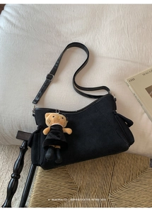 Minimalist black canvas shoulder bag with a cute cat charm on white textile background