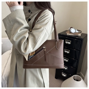 Detail of dark brown leather tote featuring white stitching and silk scarf on front zipper