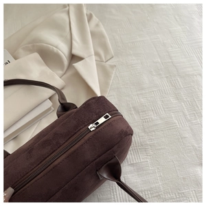 Macro shot of dark brown suede handbag with silver metal zipper and smooth leather handle