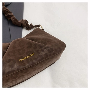 Detail of suede leopard print shoulder bag with gold Creative Cat logo and pleats