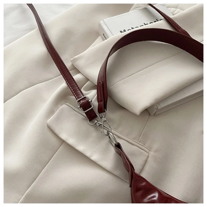 Détail des boucles argentées et de la bandoulière en cuir rouge vin du sac à bandoulière