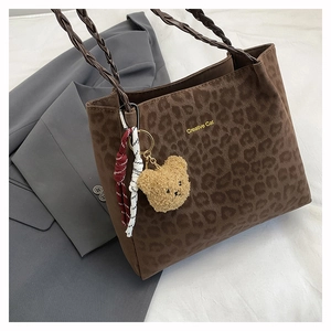 Detail of leopard print suede tote with woven handles and plush bear charm pendant