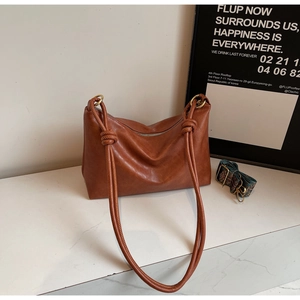 Detail of caramel leather tote bag featuring a metal ring knot and jacquard strap