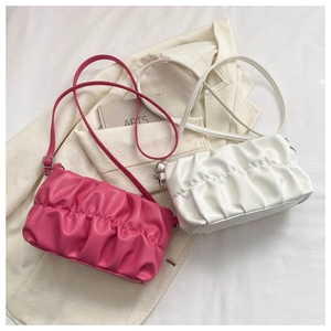 Flat lay of pink and white pleated cloud crossbody bags on minimalist background