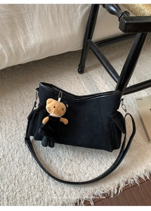 Close-up of black matte shoulder bag with utility pockets and a cute cat plush charm