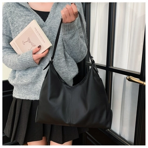 Close-up of a black matte hobo bag with vertical stitching shown on model's shoulder
