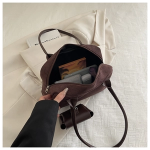 Detail of dark brown suede pillow bag interior showing large capacity with accessories