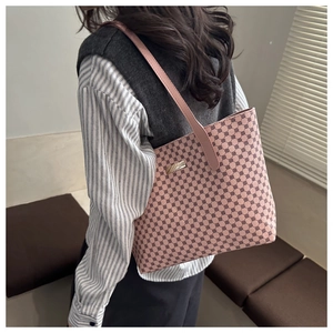 Detail of pink plaid tote bag featuring leather texture and metallic logo plate