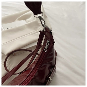 Détail du sac hobo bordeaux brillant avec fermeture éclair argentée et texture cuir