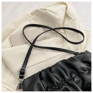 Close-up of black pleated cloud bag with adjustable leather strap and silver metal buckle