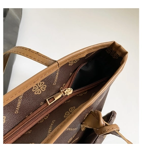 Close-up of brown tote bag zipper closure with golden hardware and pattern detail