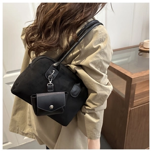 Detail of black suede Boston bag with mini pouch showing capacity and shoulder fit