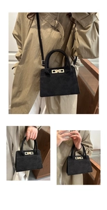 Détail de la texture en daim noir et du fermoir en métal doré sur le sac à main rétro