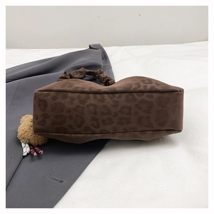 Detail of leopard print underarm bag with ruffled handle and plush bear charm