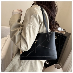 Detail of a large black tote bag featuring distinctive white contrast stitching for a modern look