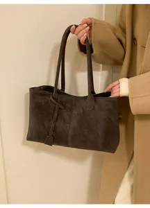 Detail of dark brown tote bag featuring long shoulder straps and knotted leather pendant charm