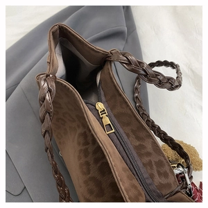 Close-up of leopard print tote bag featuring a metallic zipper and braided handle detail